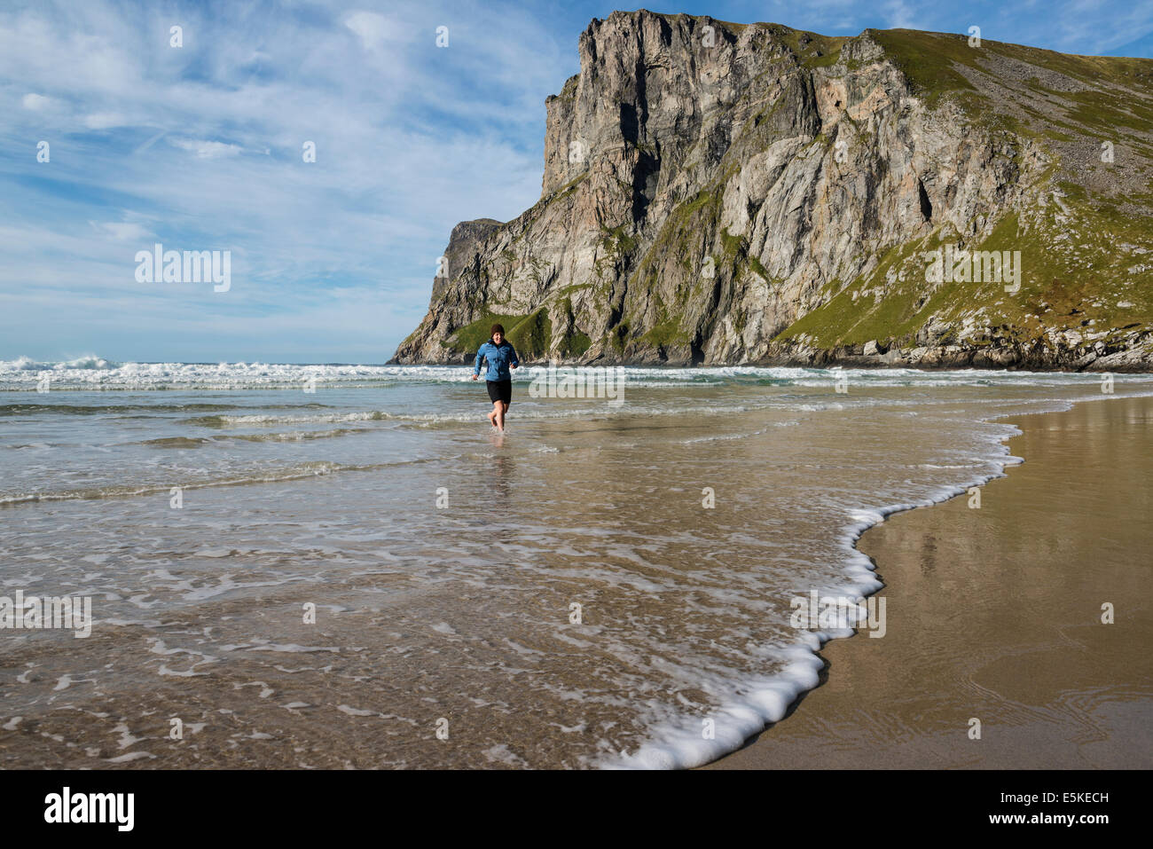 Weibliche Wanderer geht im Meer unter Ryten Kvalvika Beach, Moskenesøy, Lofoten Inseln, Norwegen Stockfoto