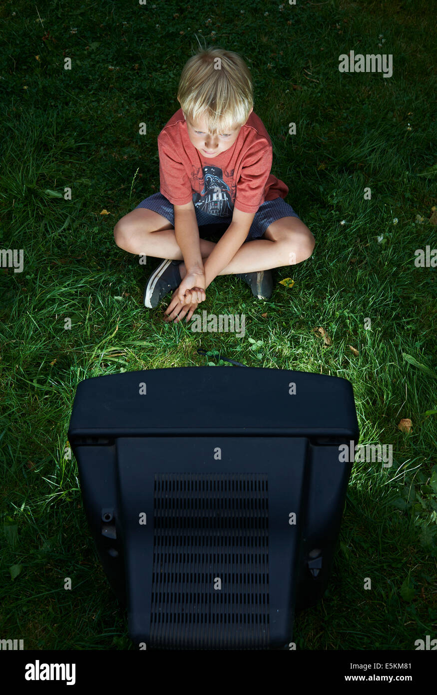 Kind blonde junge Fernsehen in Hof, draußen im grünen Rasen, emotionale, Gesichts Ausdruck, Grimassen schneiden, Grinsen Stockfoto