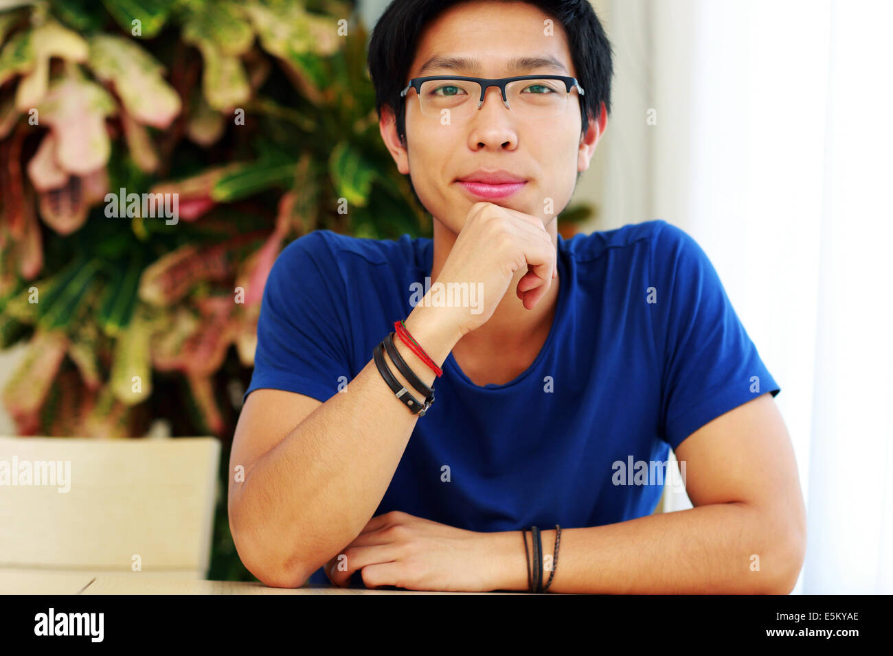 Glücklich asiatischen Mann mit Brille, die am Tisch sitzen Stockfoto