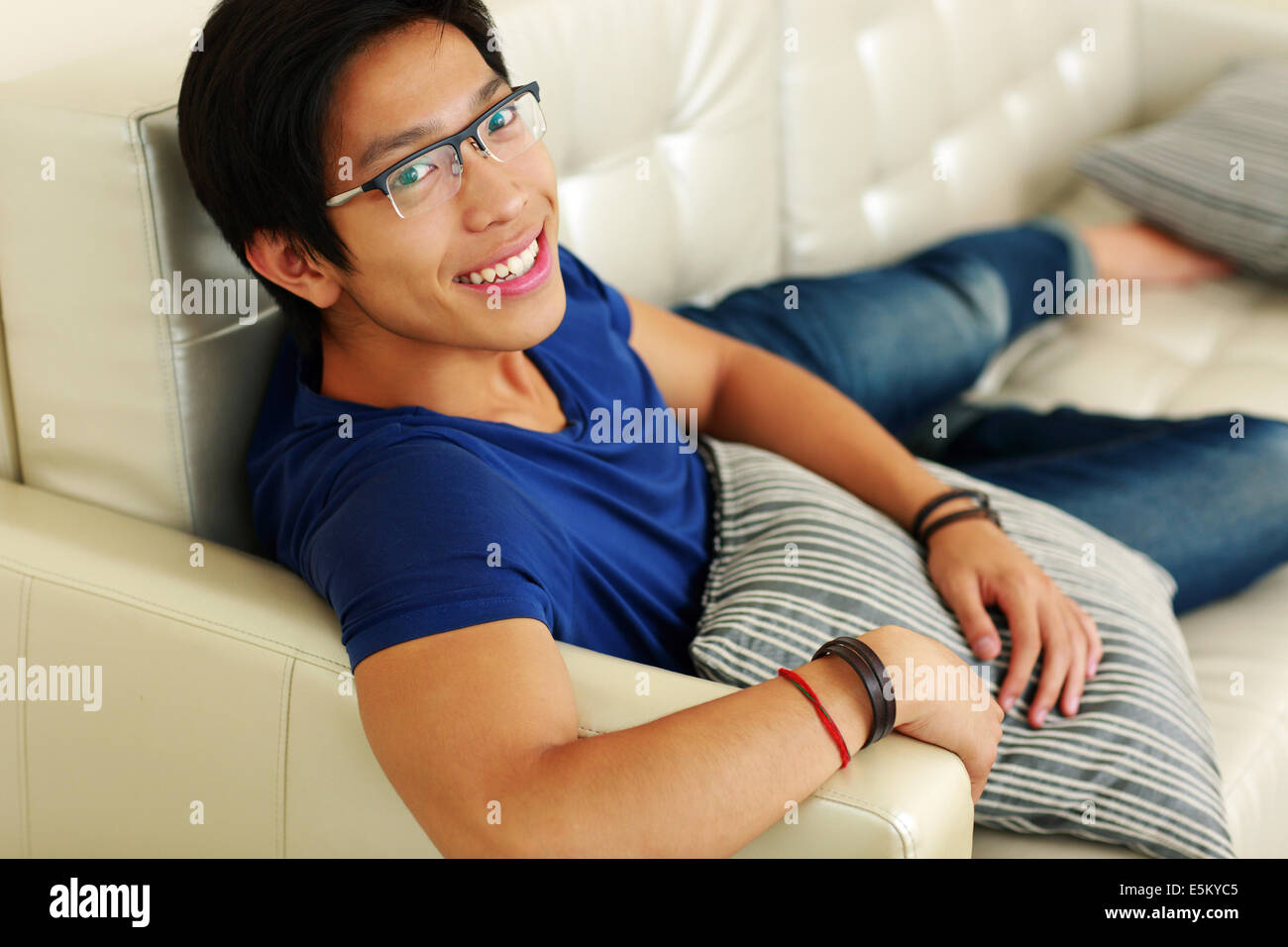 Lächelnder asiatischen Mann zu Hause auf dem Sofa entspannen Stockfoto