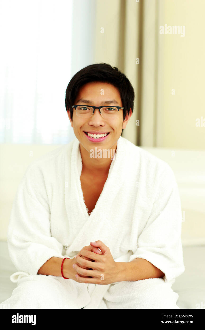 Lächelnder Mann im Bademantel sitzen auf dem Bett im Schlafzimmer Stockfoto
