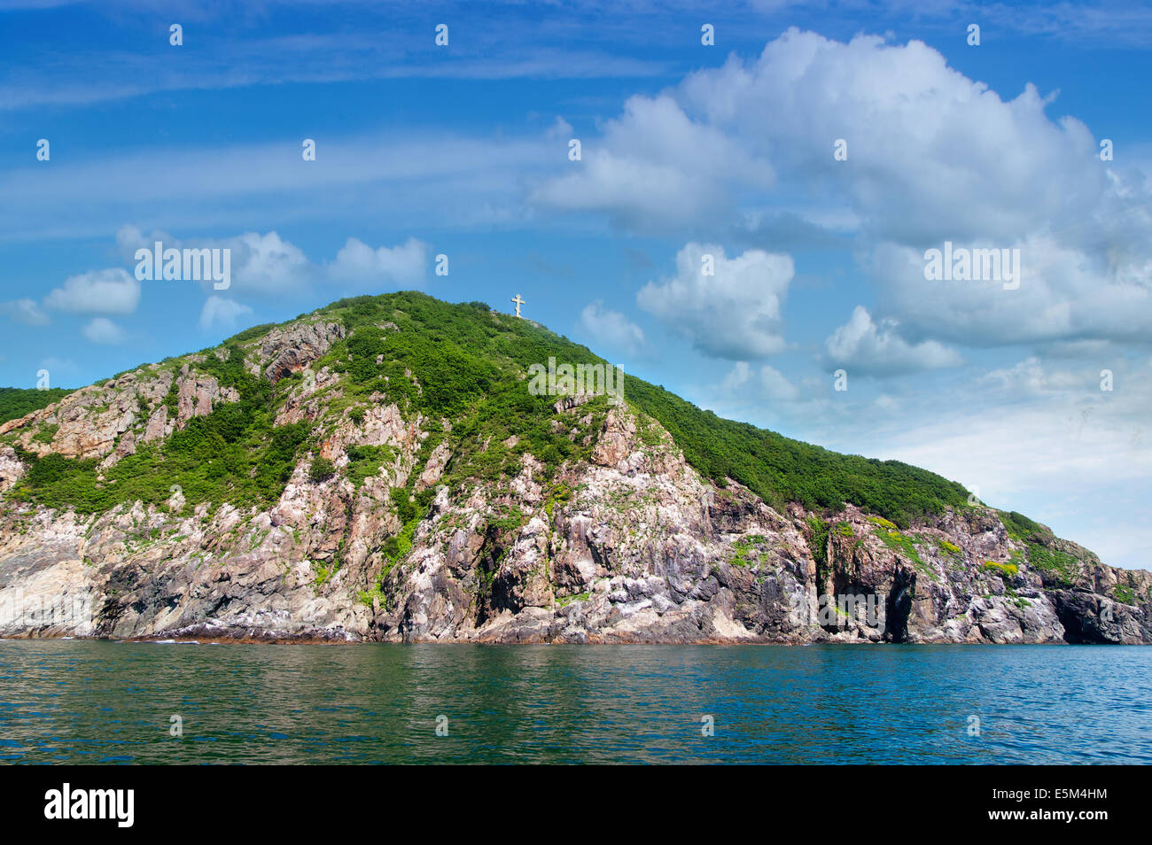 Felsen, Meer und orthodoxe Kreuz auf den blauen Himmel - Fox Island am Eingang zum Hafen von Nachodka-Russland Stockfoto