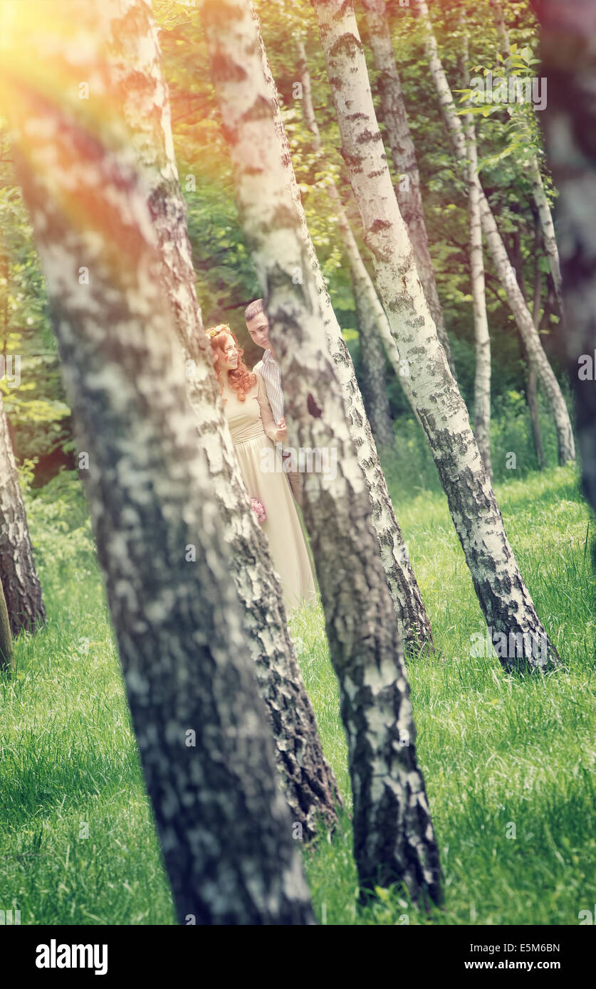 Foto des jungen Paares durch zwei Birken, Spaß im Park, hellen Sonnenstrahlen, Liebesbeziehung, Sommerferien Stockfoto