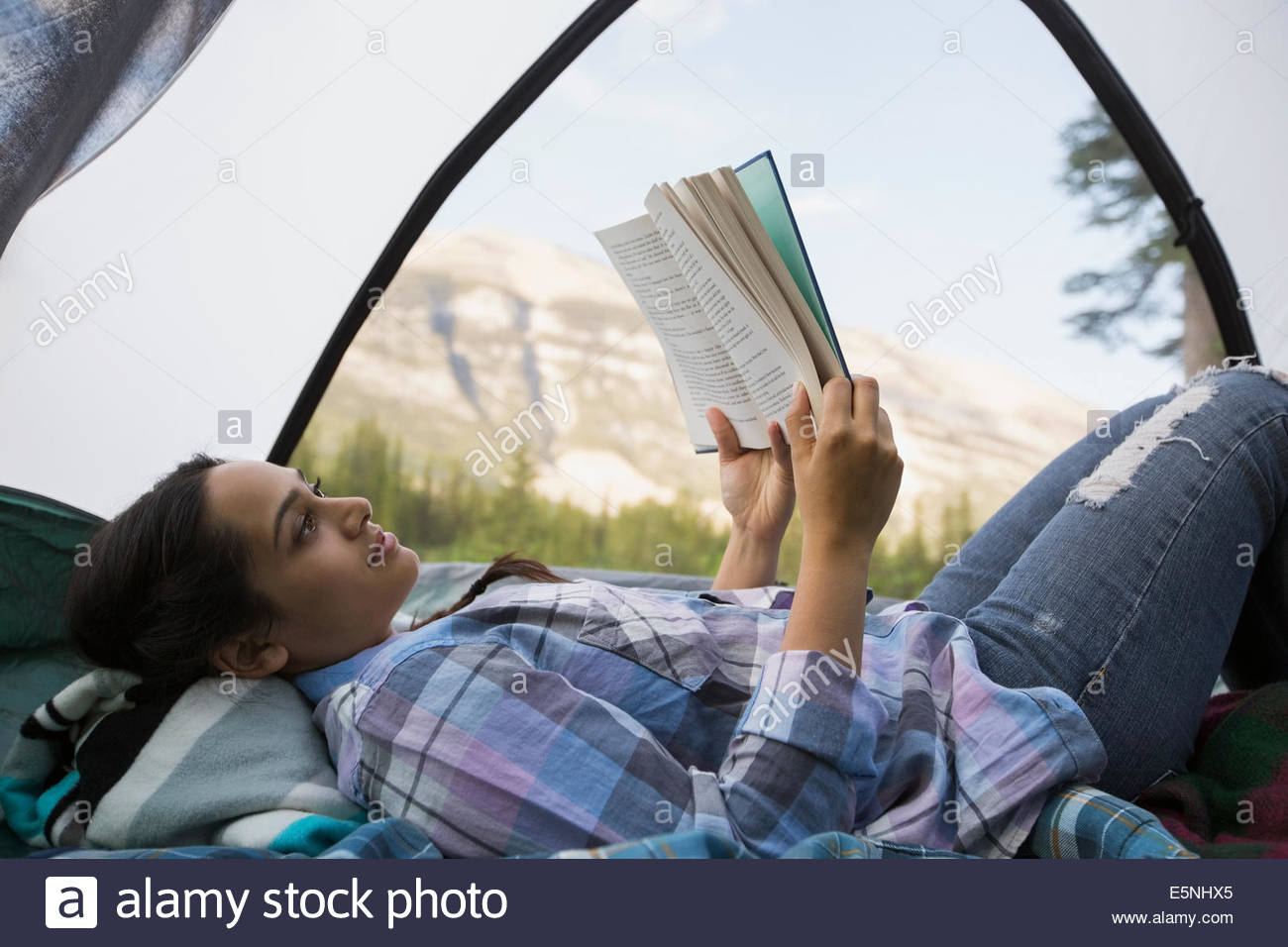 Frau Lesebuch im Zelt mit Blick auf die Berge Stockfoto