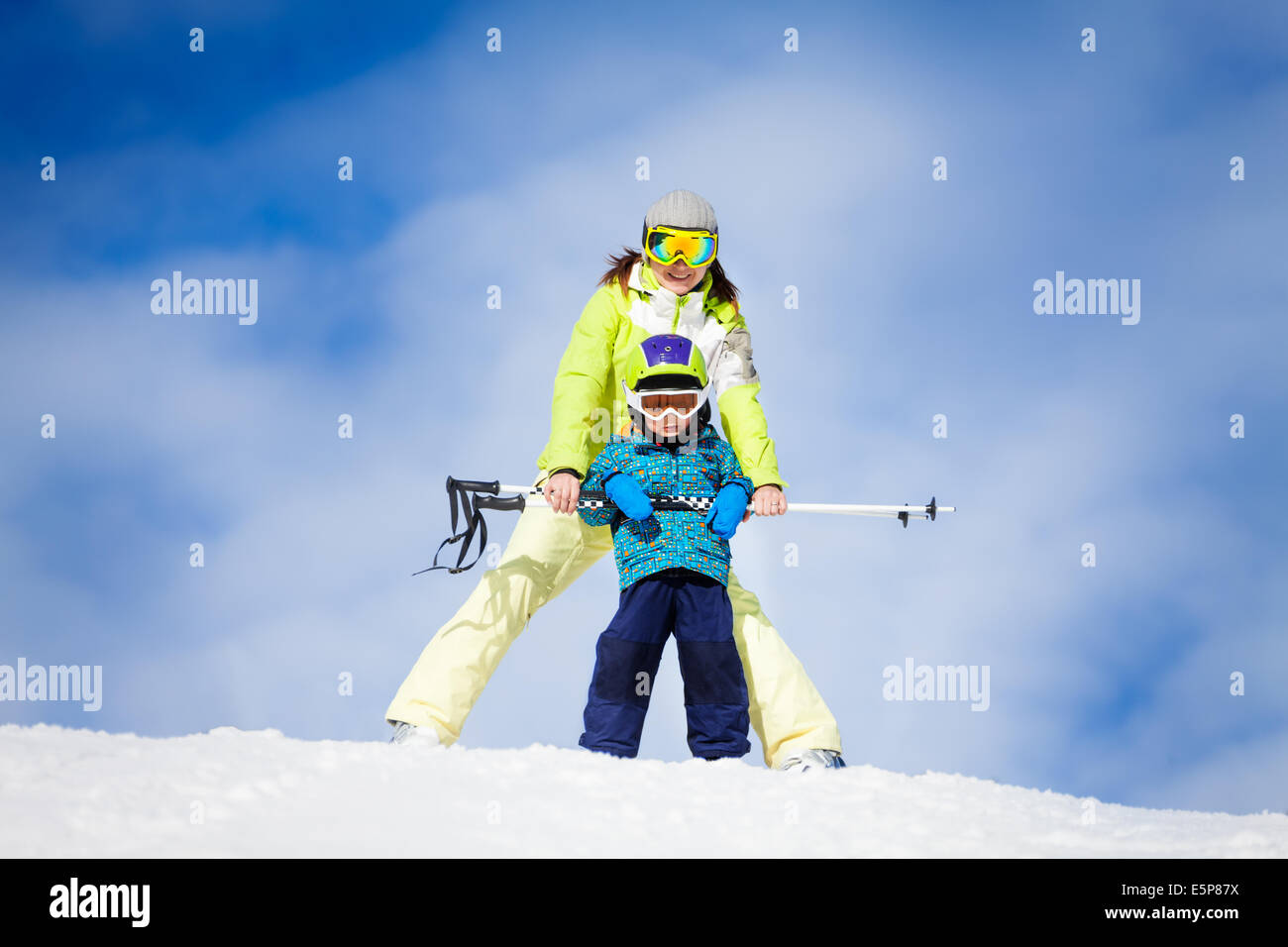 Mutter und Kind in Masken stehend mit Ski-Umfragen Stockfoto