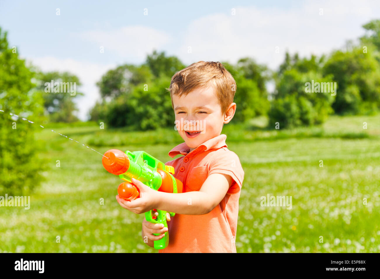 Kleiner Junge spielt mit einer Wasserpistole Stockfoto