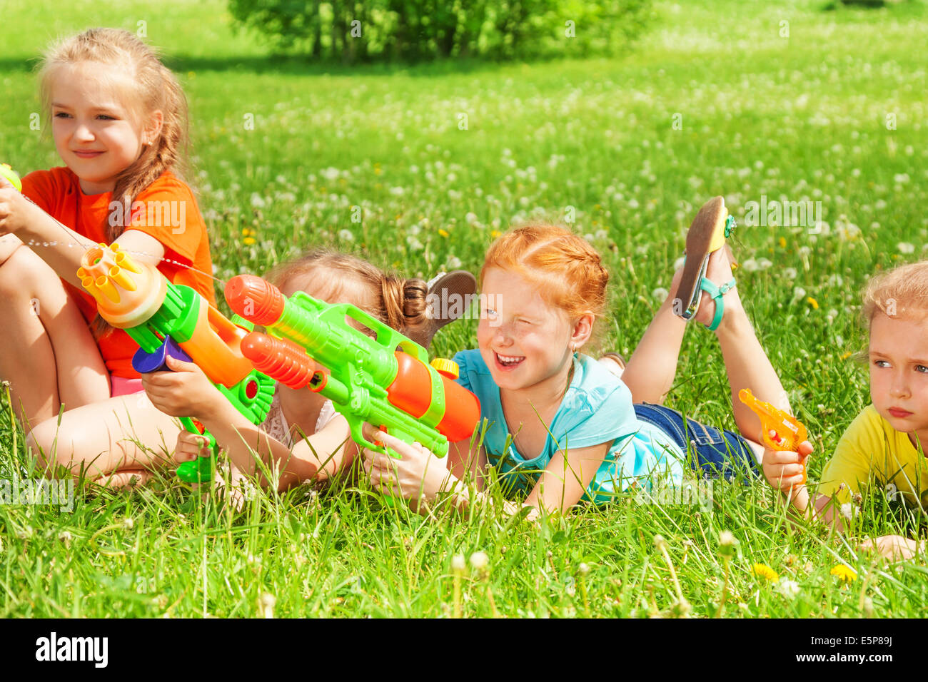 Kinder spielen mit Wasserpistolen auf einer Wiese Stockfoto