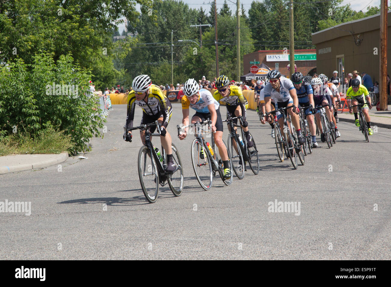 Radrennfahrer fahren auf einer Runde des Criterium um eine Straßenecke, die Teil des Wettbewerbs Tour de Bowness in der Gemeinde Bowness in Calgary, Alberta, Kanada, ist. Ein Kriterium ist ein schnelles Radrennen auf einer kurzen Strecke mit den Straßen der Stadt für den Verkehr gesperrt. Stockfoto