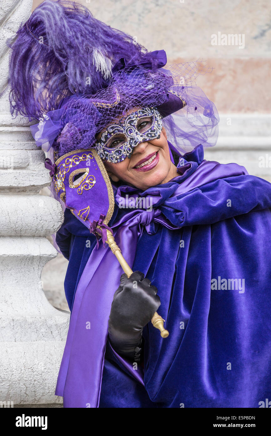 Ältere Frau in Blau mit lila Kostüm vor der Kirche San Zaccaria während des Karnevals in Venedig. Stockfoto
