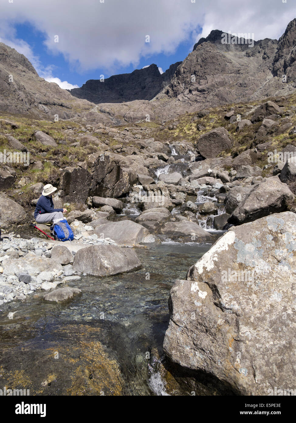 Frau sitzt von Tumbling Stream von Allt Coire Lagan mit Black Cuillin Berge, Glenbrittle, Isle Of Skye, Schottland, Vereinigtes Königreich Stockfoto