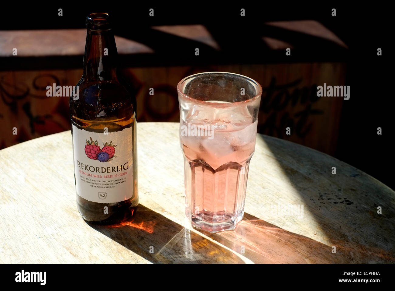 Glas und Flasche Frucht gewürzten Apfelwein saß auf einem sonnenbeschienenen Tisch in einer bar Stockfoto
