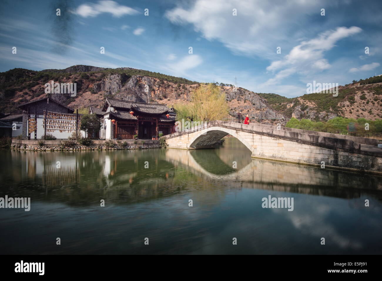 Guan Yin Gorge Park mit einem Schauspieler in Monkey King Kostüm sitzen auf der Brücke warten auf Besucher, Lijiang, Yunnan, China Stockfoto