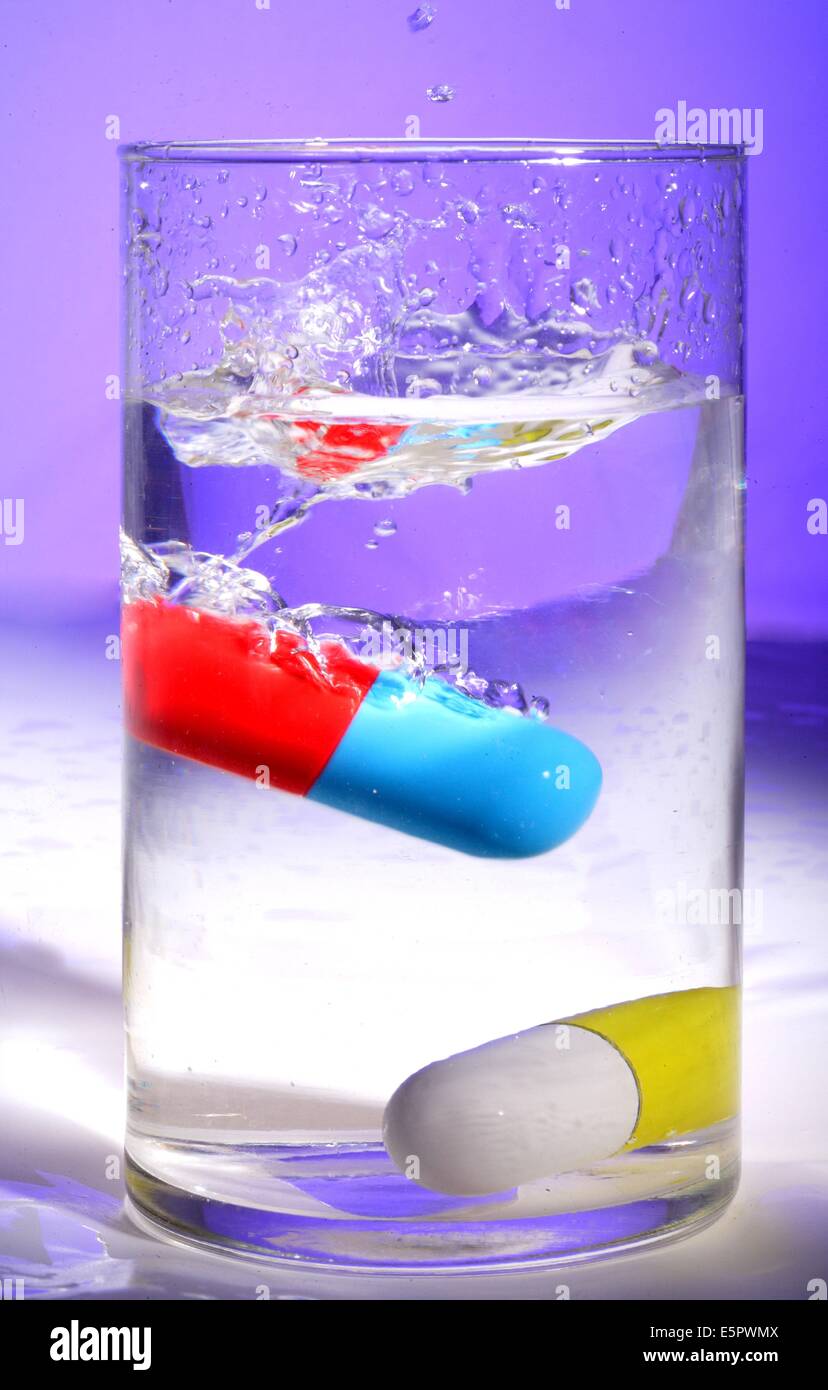 Droge-Kapseln auf ein Glas Wasser. Stockfoto