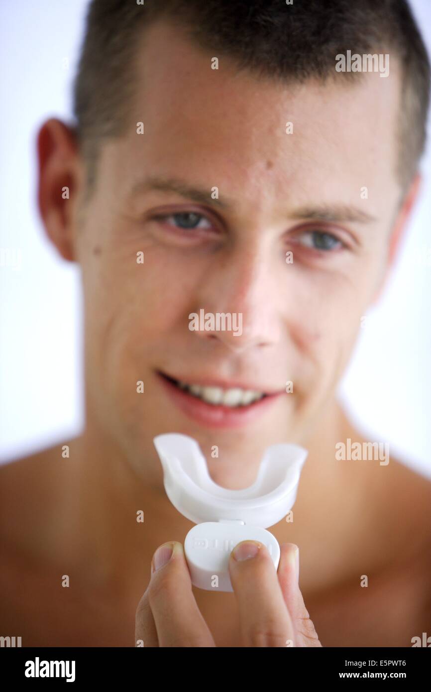Zähne bleichen, Mann Anwendung einen Schaum mit Bleaching Wirkstoffen in eine Elektrolumineszenz GAP-Schiene. Stockfoto