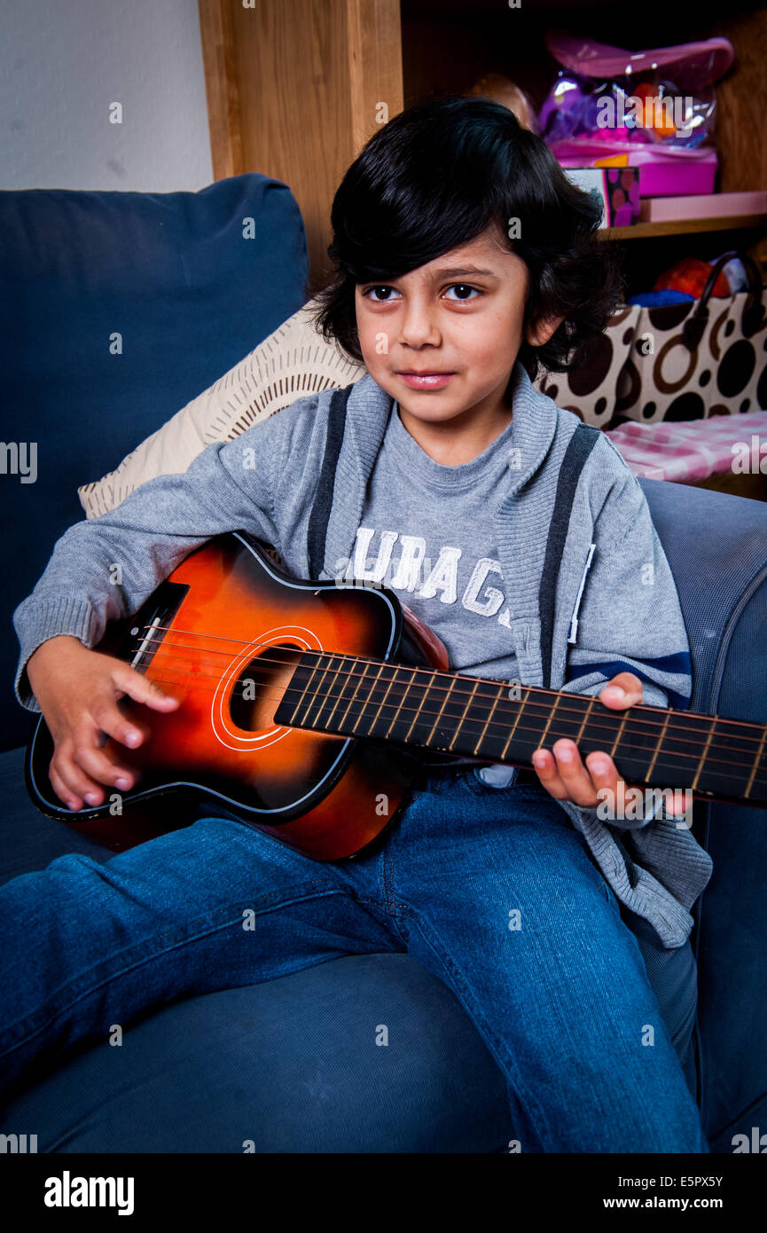 Jungen im Alter von 6-7-8 spielen mit Gitarre auf sofa Stockfoto