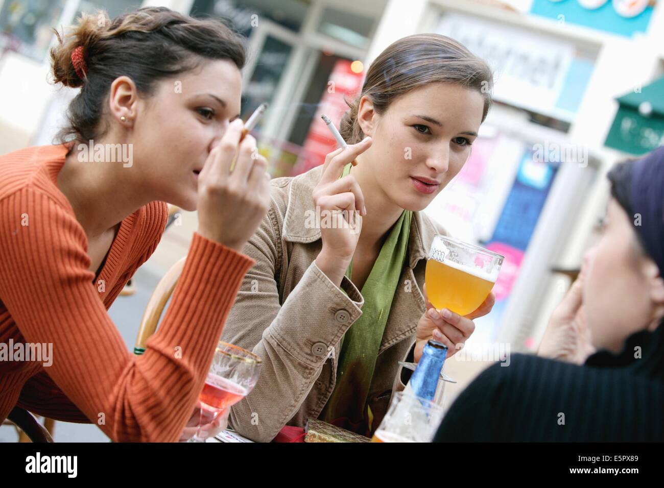 Frauen rauchen und trinken auf einer Terrasse. Stockfoto