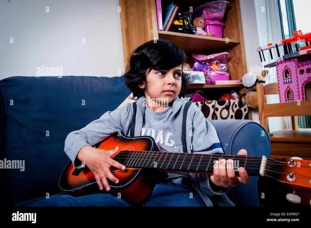 Jungen im Alter von 6-7-8 spielen mit Gitarre auf sofa Stockfoto