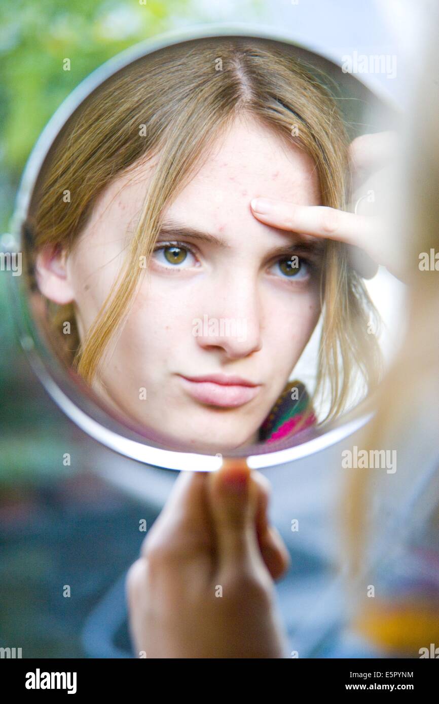 Teenager-Mädchen ihr Gesicht im Spiegel, für Acnea Pickel oder andere Hautprobleme zu überprüfen. Stockfoto
