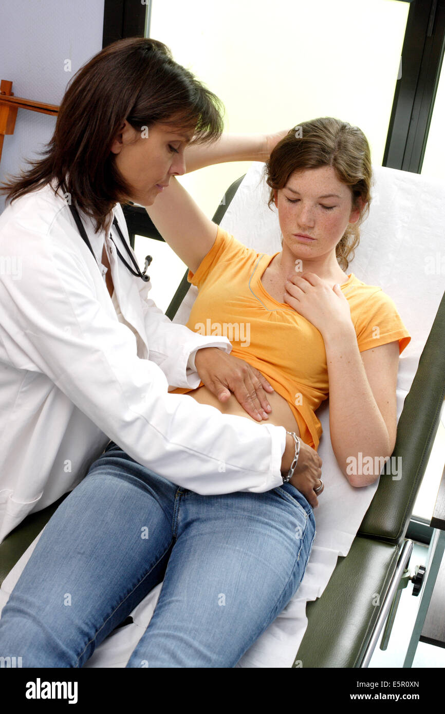 Arzt untersucht den Bauch eines weiblichen Teenagers durch Abtasten. Stockfoto