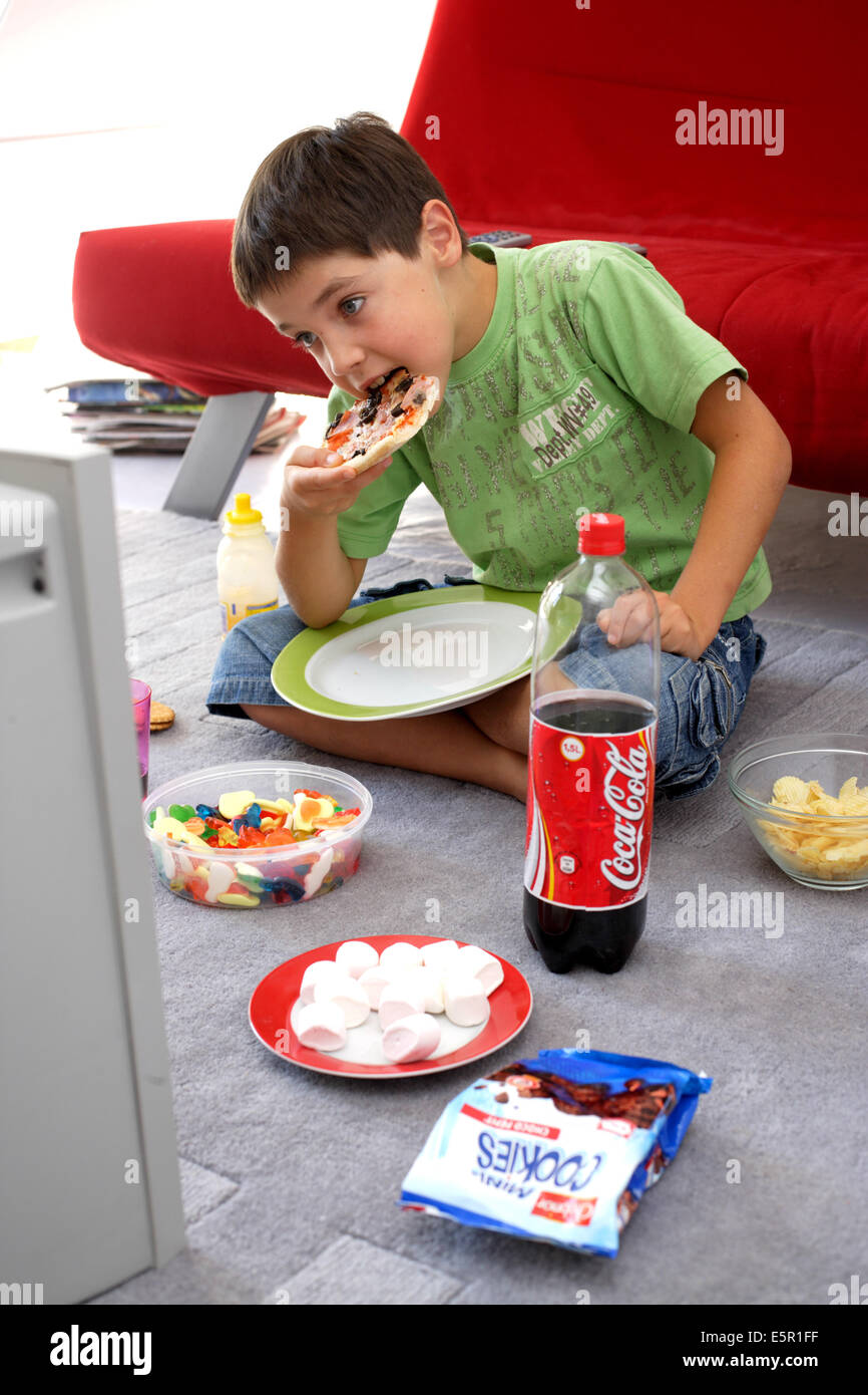 Kind Naschen vor dem Fernseher. Stockfoto