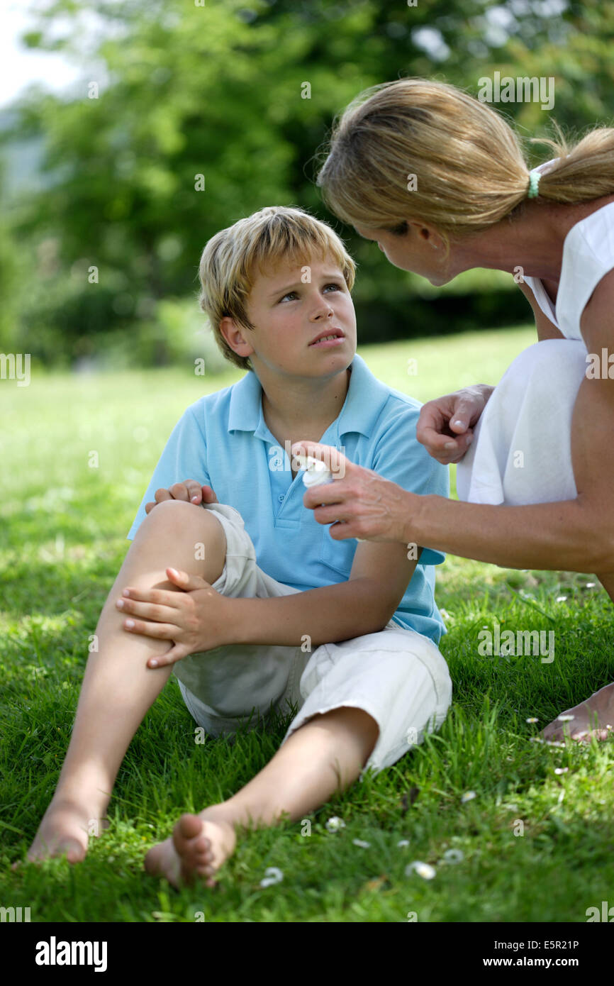 Frau Anwendung Spray auf juckende Haut ihres Sohnes nach Insektenstich. Stockfoto