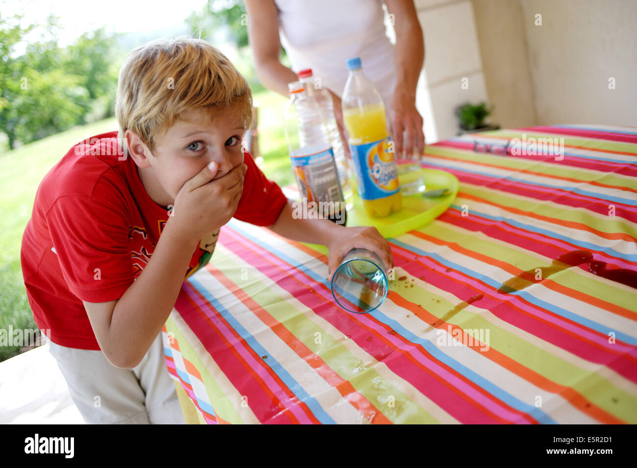 Mischiefly junge verschütten Glas auf dem Tisch. Stockfoto