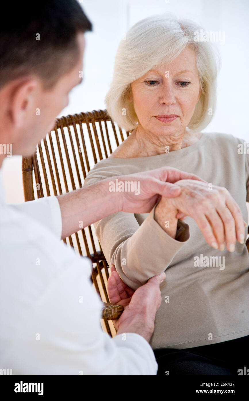 Arzt untersucht das Handgelenk der Seniorin. Stockfoto