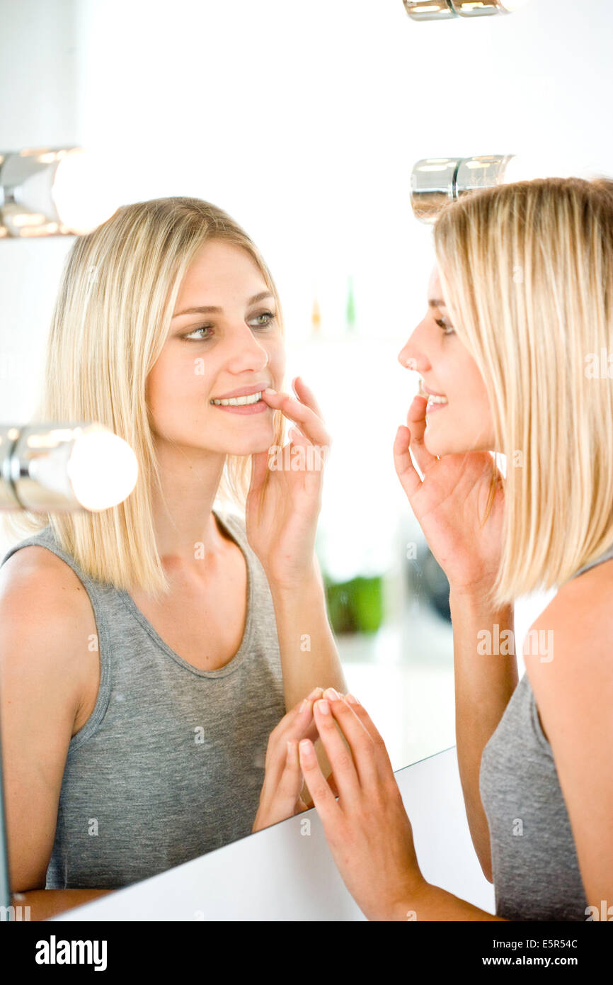 Frau ihr Gesicht im Spiegel zu beobachten. Stockfoto