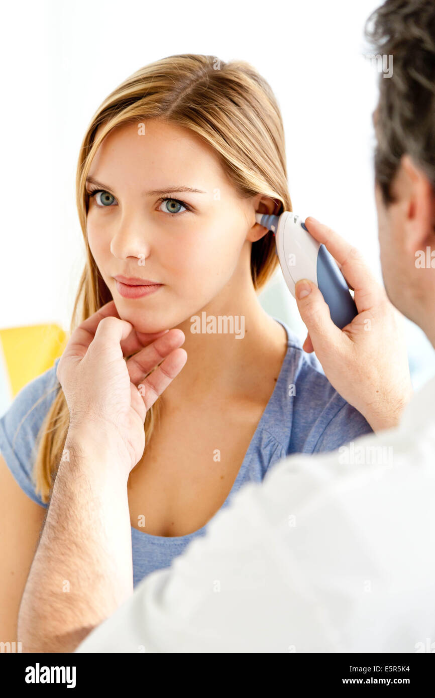 Allgemeinmedizin Arzt mit einer klanglichen Thermometer zur Messung der Temperatur des Patienten. Stockfoto