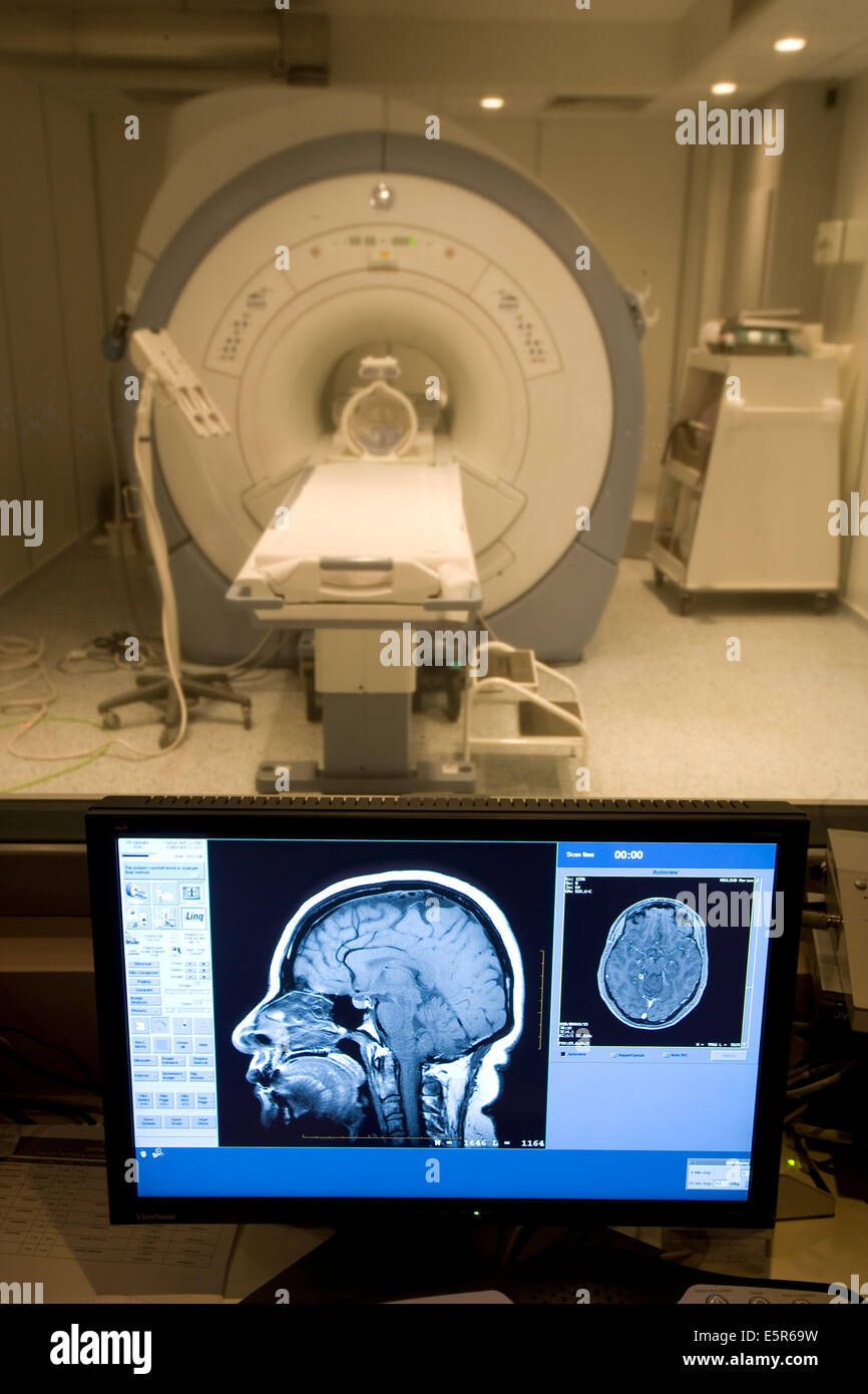 Geschlossene Geometrie Magnet-Resonanz-Tomographie (MRT) Einheit, 3 Tesla mit einem MRI Gehirnscan auf dem Kontrollbildschirm. Stockfoto