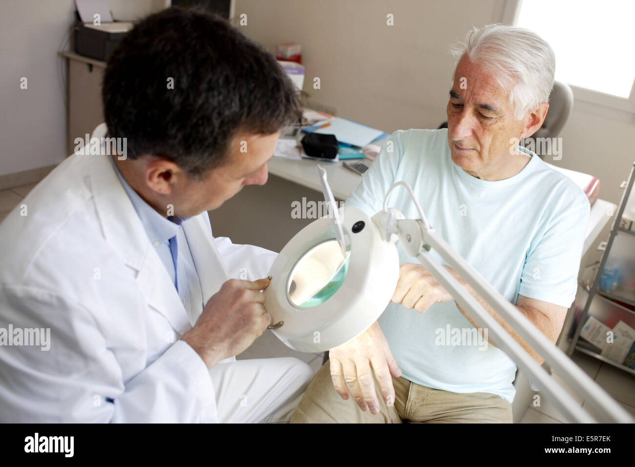 Hautarzt untersuchen die Beauty-Marke eines Patienten für Melanom-Screening. Stockfoto