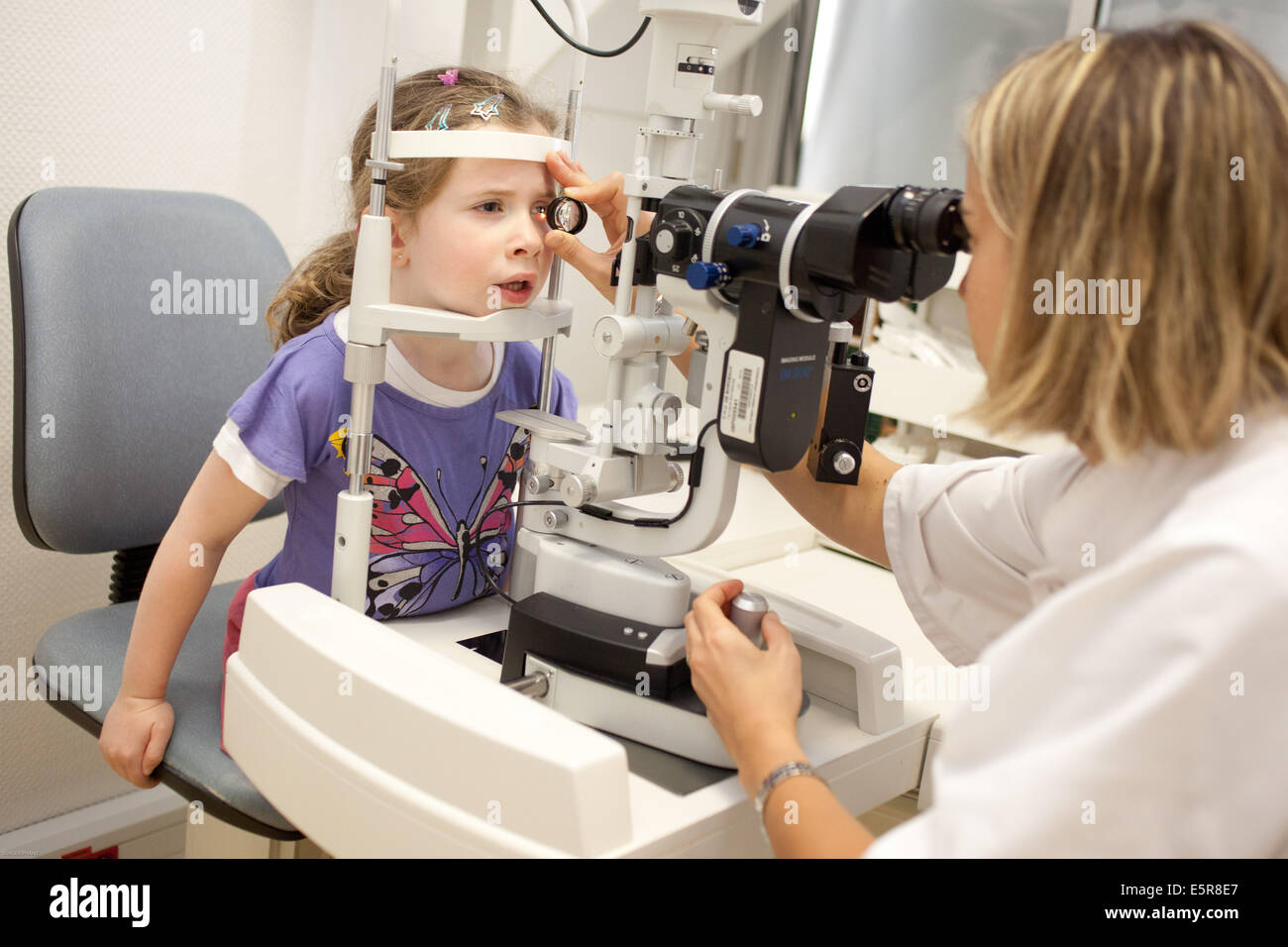 Augenarzt untersucht das Innere des Auges eines kleinen Jungen mit einem Ophthalmoskop, Abteilung für pädiatrische Ophthalmologie, Stockfoto
