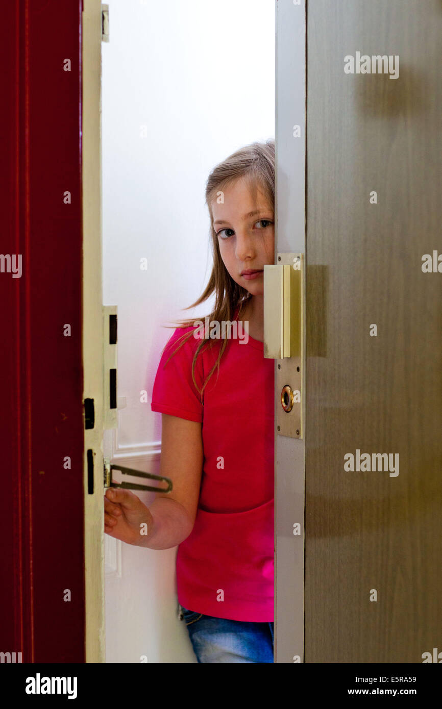 11 Jahre altes Mädchen Öffnen einer Tür mit einer Tür Wache. Stockfoto