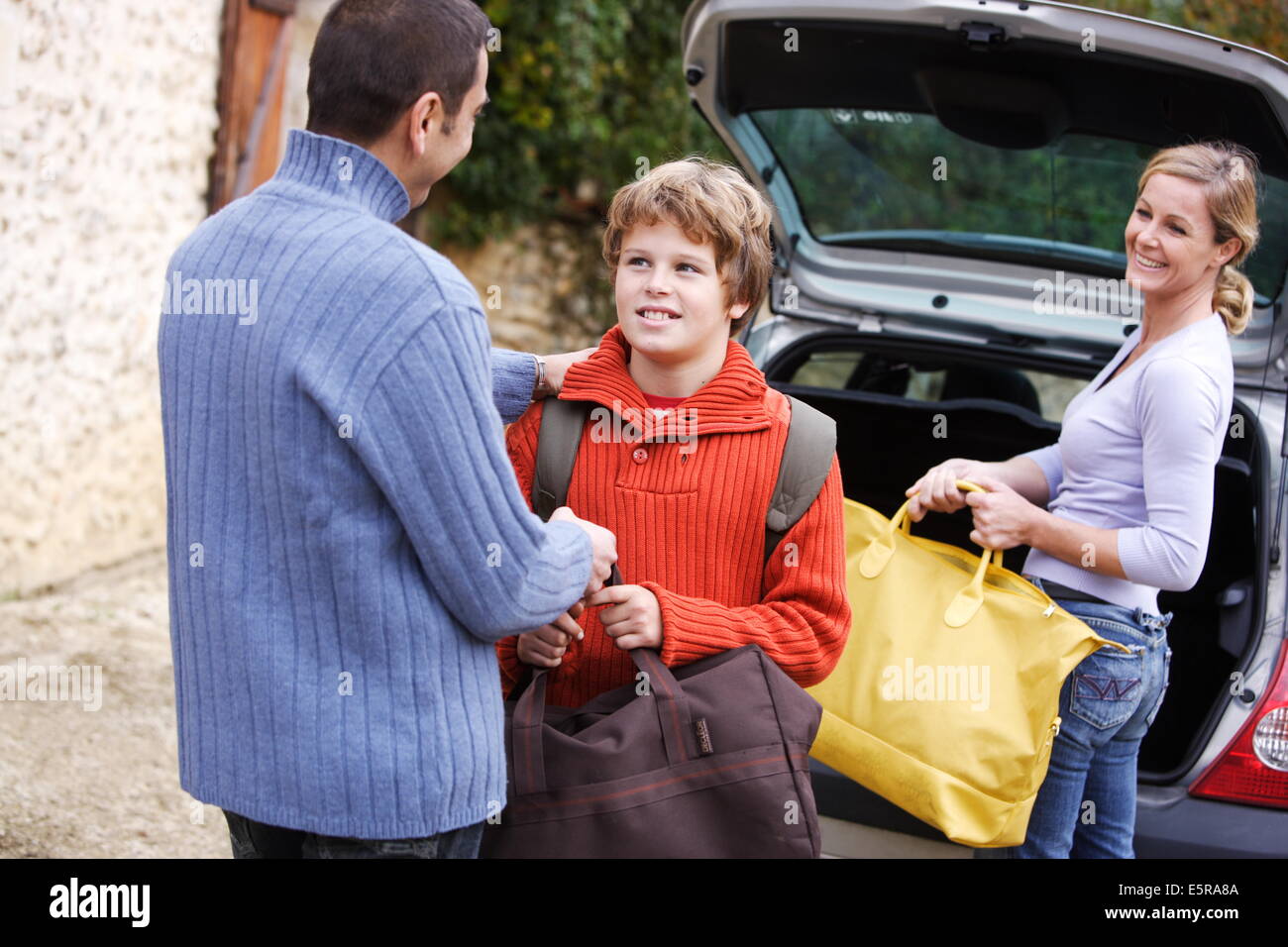12 Jahre alter Junge und Eltern mit Reisetaschen. Stockfoto