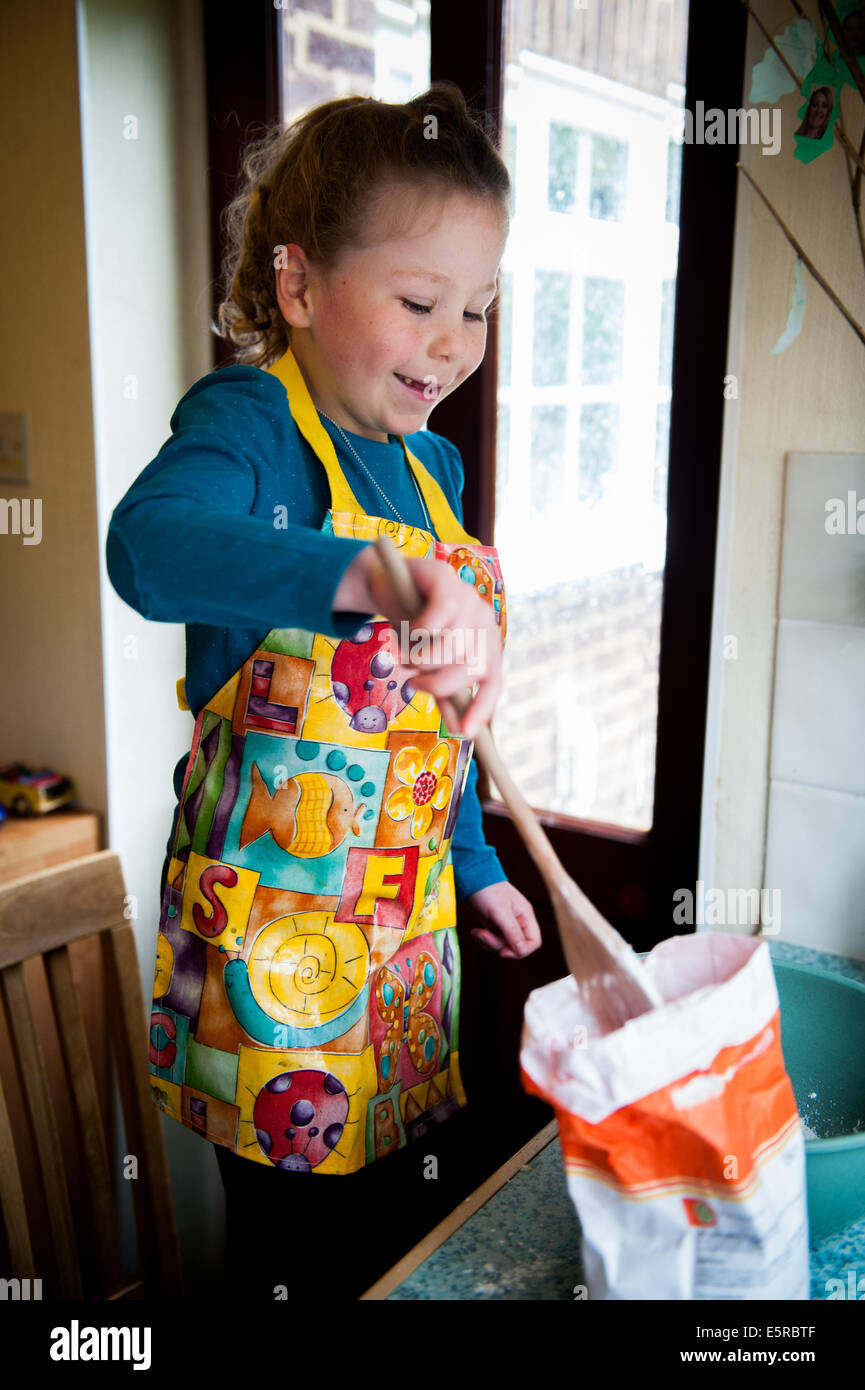 Mädchen von 6 7 8 9 einen Kuchen zu backen / Flickschusterei mit Mehl Stockfoto