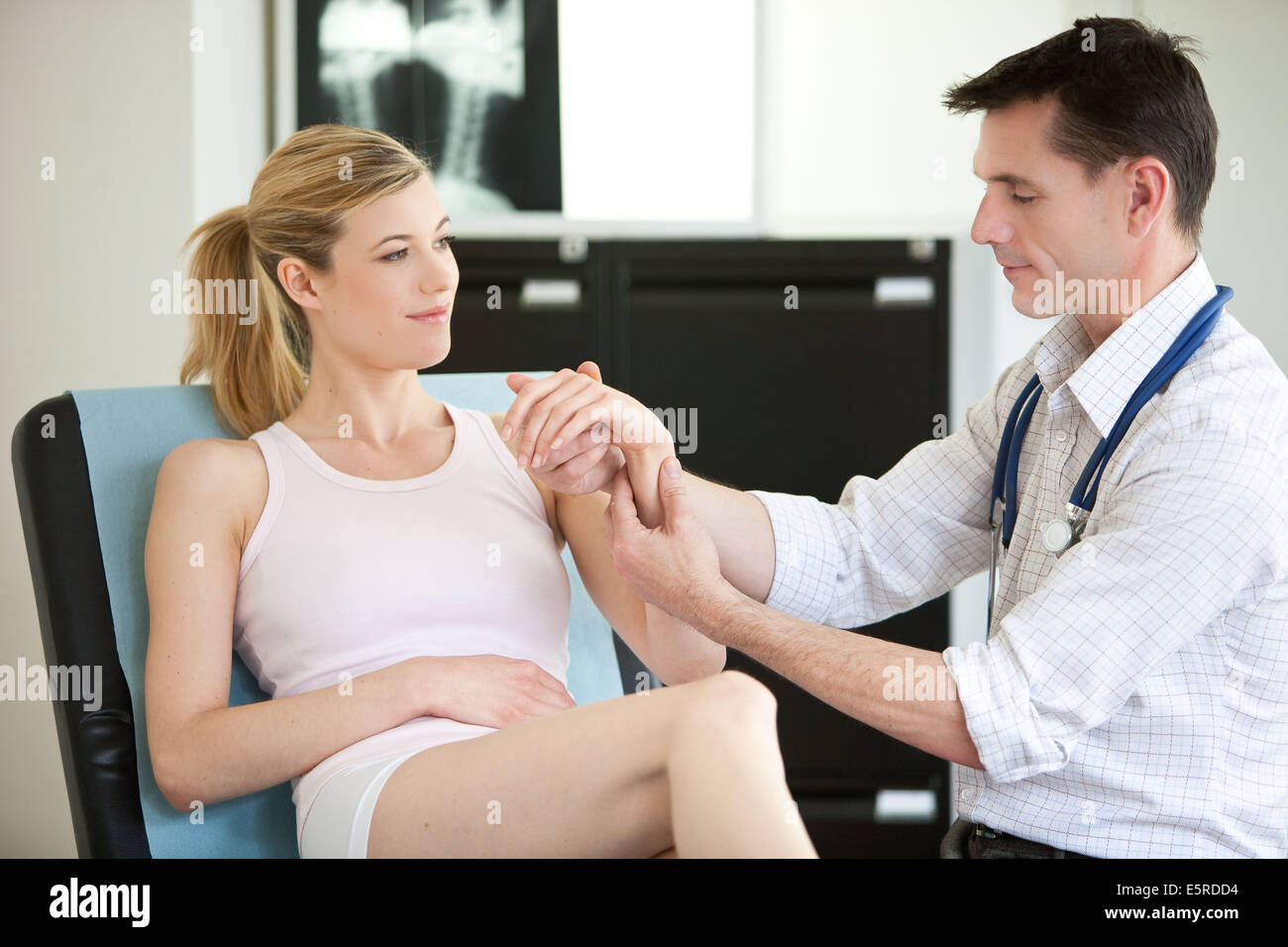 Arzt untersucht Handgelenk einer Patientin. Stockfoto