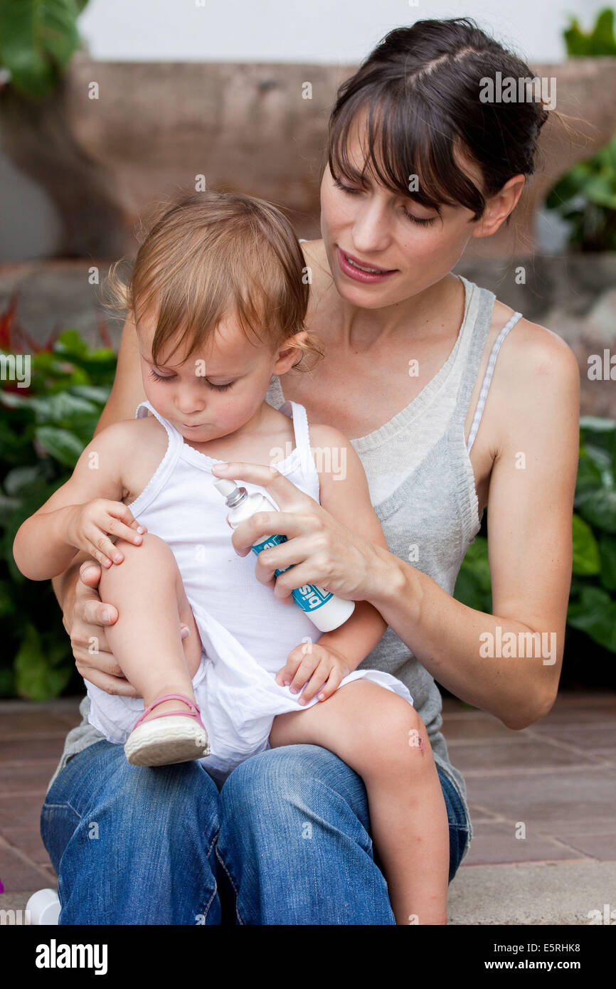 Mutter Anwendung Spray auf ihre 20 Monate altes Baby. Stockfoto