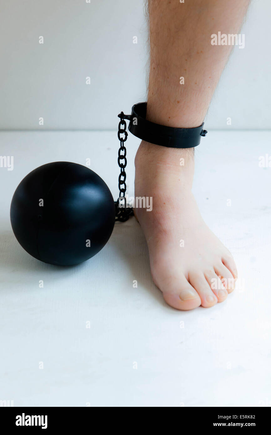 Ball und Kette bis zum Knöchel eines Mannes befestigt. Stockfoto