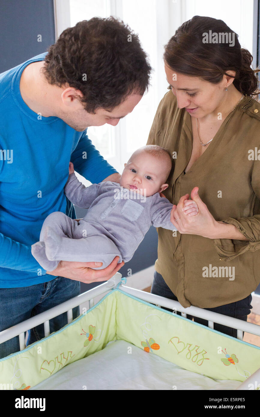 Mutter und Vater ihre 5 Monate altes Baby Boy ins Bett setzen. Stockfoto