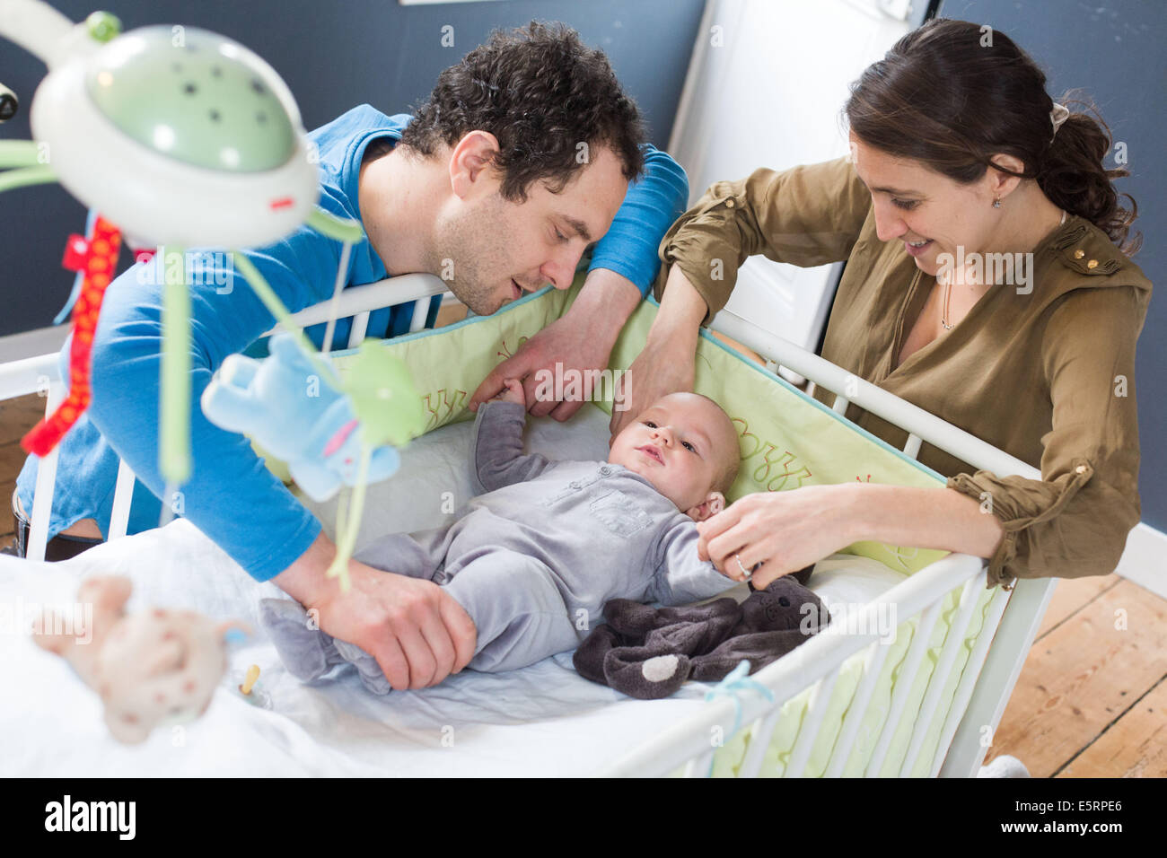 Mutter und Vater ihre 5 Monate altes Baby Boy ins Bett setzen. Stockfoto