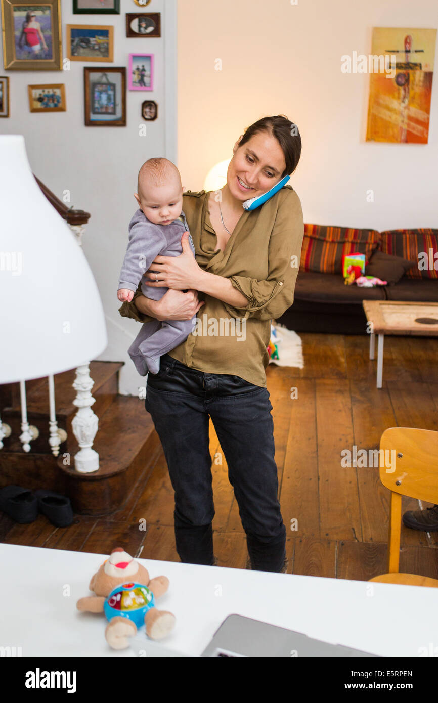 Mutter am Telefon halten ihr 5 Monate altes Baby Boy. Stockfoto