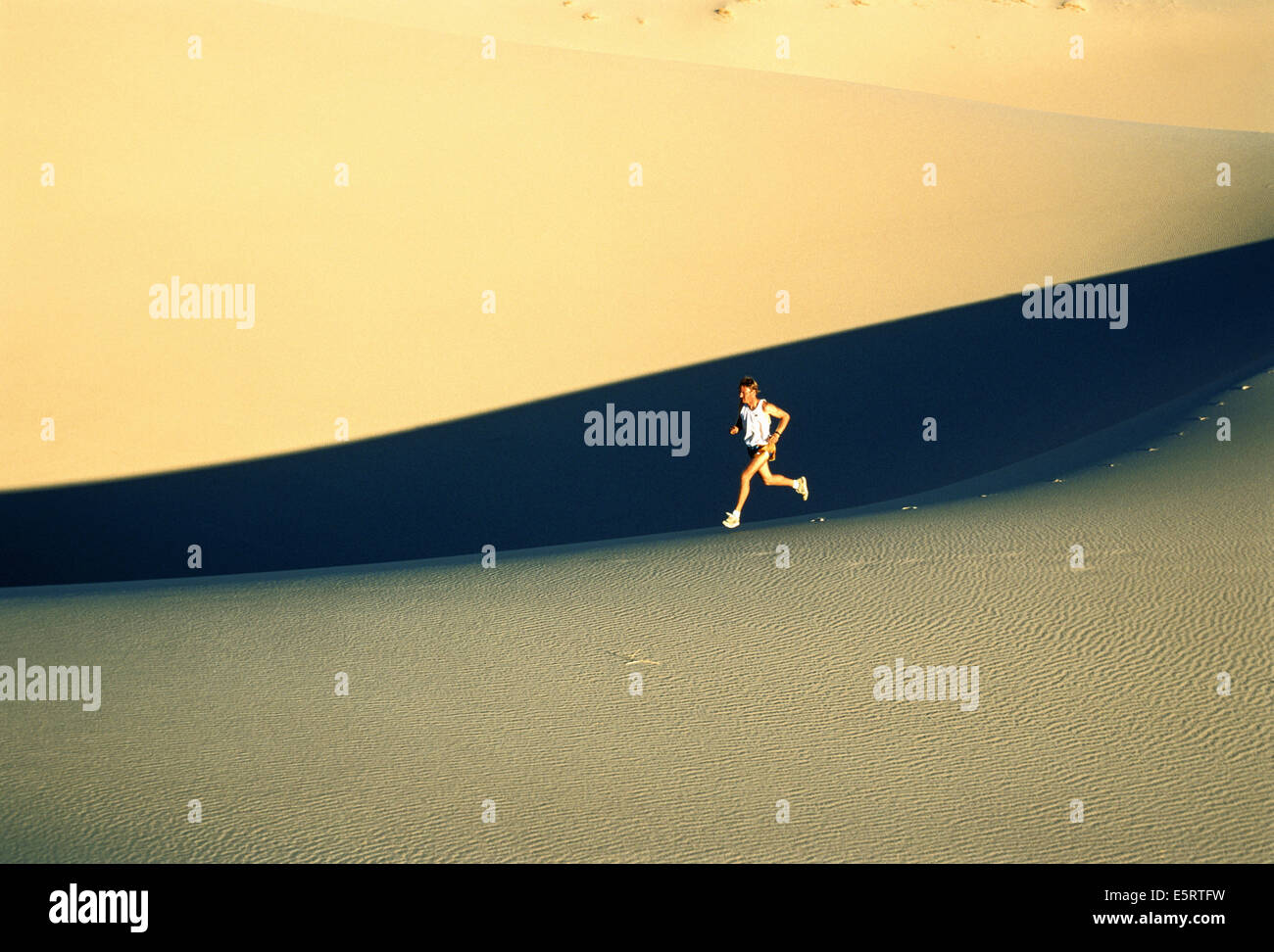 Mann läuft über Sanddüne Stockfoto