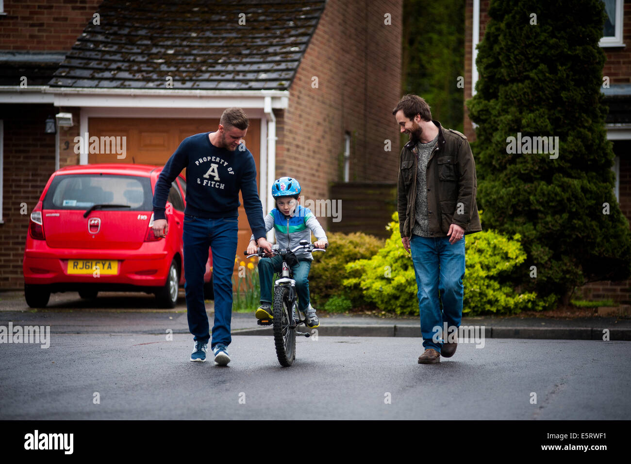 2 männliche Partner / Eltern / Freunde unterrichten junge, mit dem Fahrrad Stockfoto
