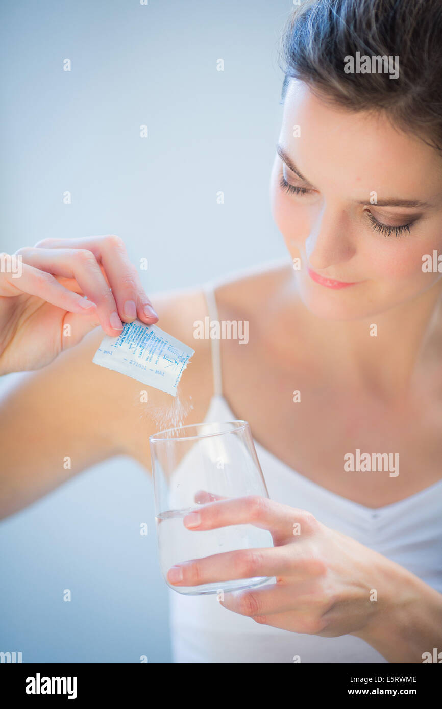 Frau Medizin Pulver in einem Glas Wasser auflösen. Stockfoto
