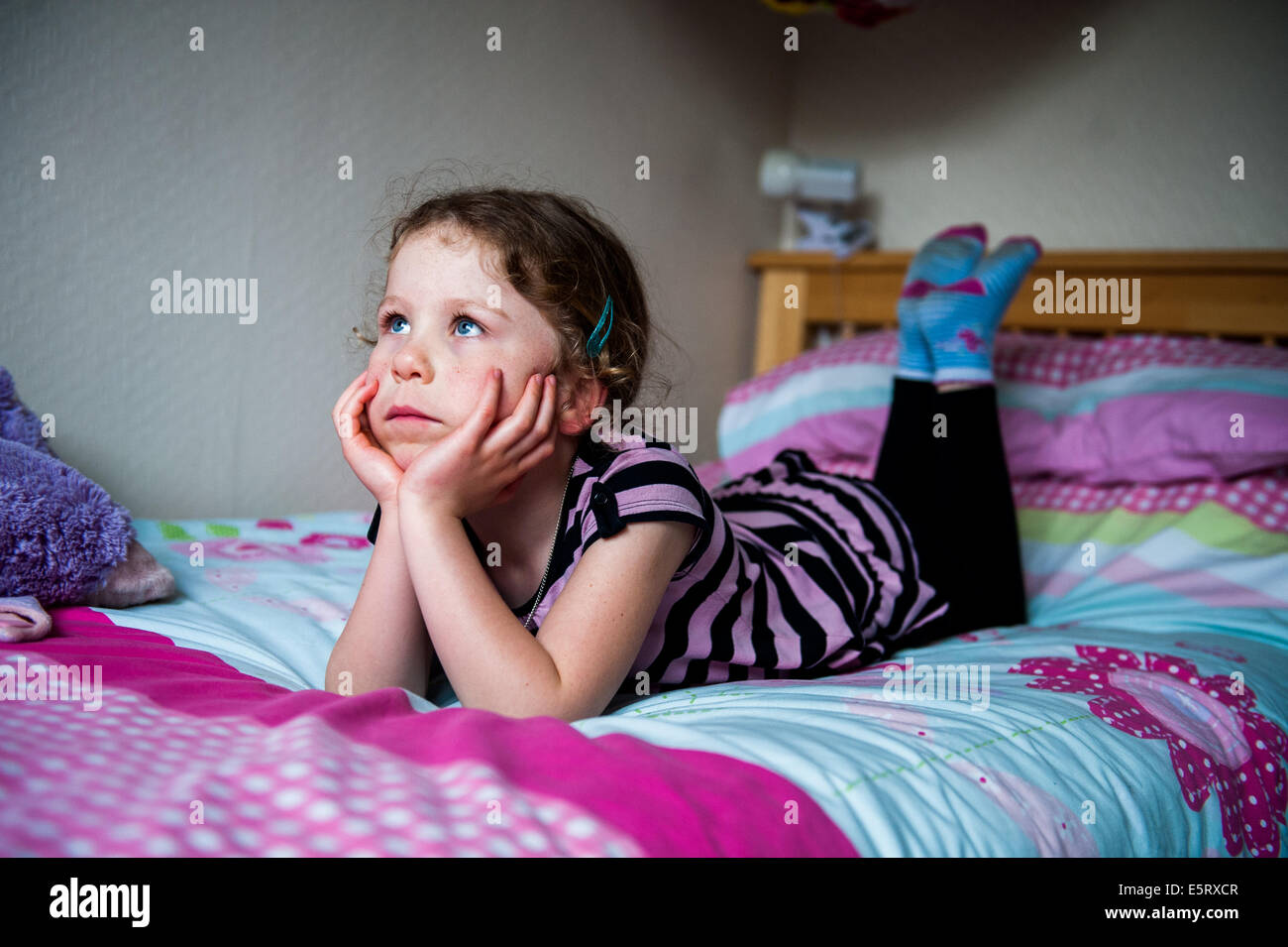 8, 9, 10 jährige Mädchen auf der Suche nachdenklich oder gelangweilt auf Bett Stockfoto