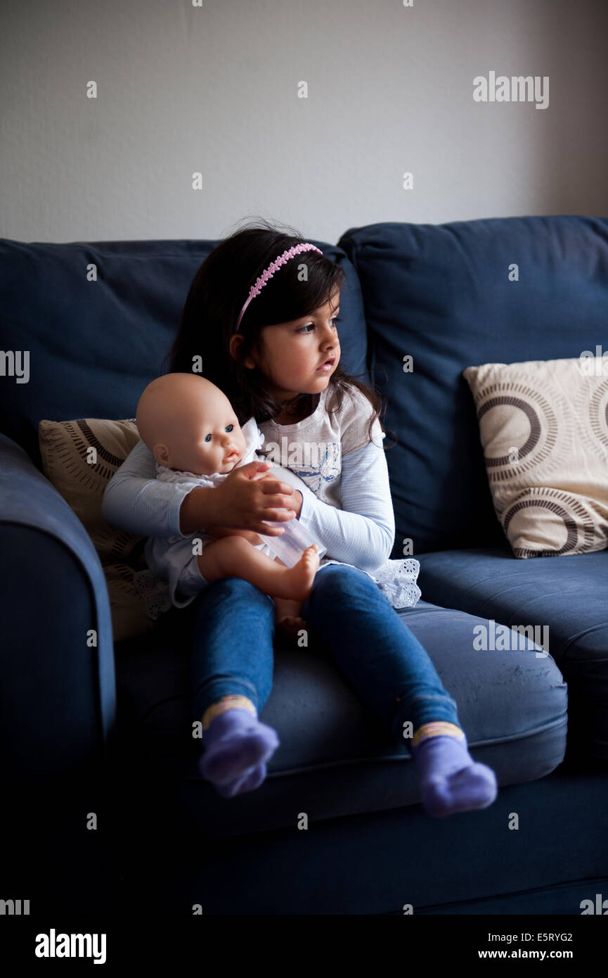 6 Jahre altes Mädchen mit Puppe, Blick aus dem Fenster Stockfoto