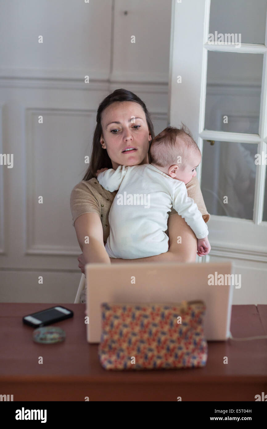 Frau mit Laptop-Computer mit ihren 4 Monate alten Baby. Stockfoto
