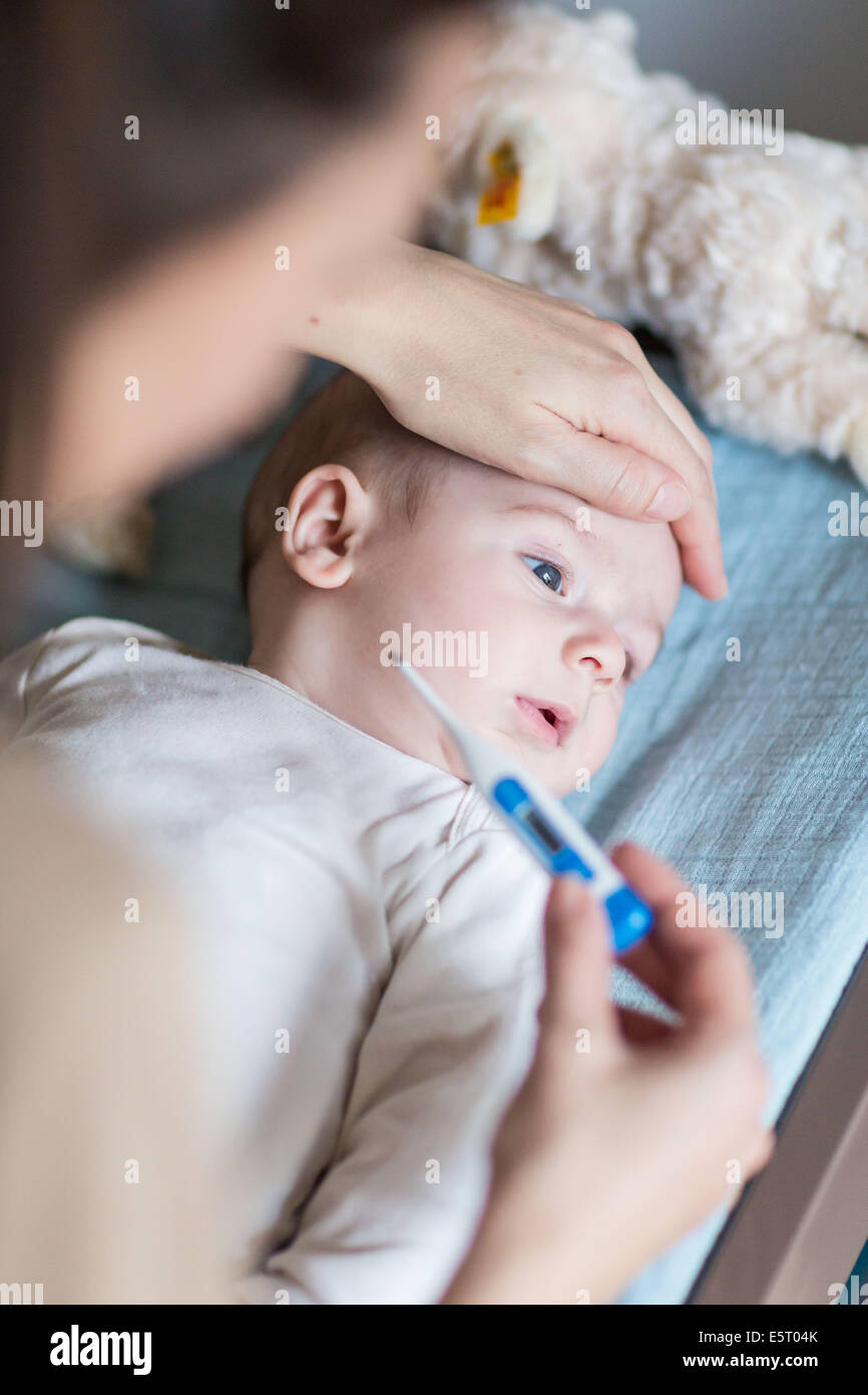 Mutter, überprüfen die Temperatur ihres 4 Monate alten fiebrigen Baby jungen mit einem digitalen Thermometer. Stockfoto