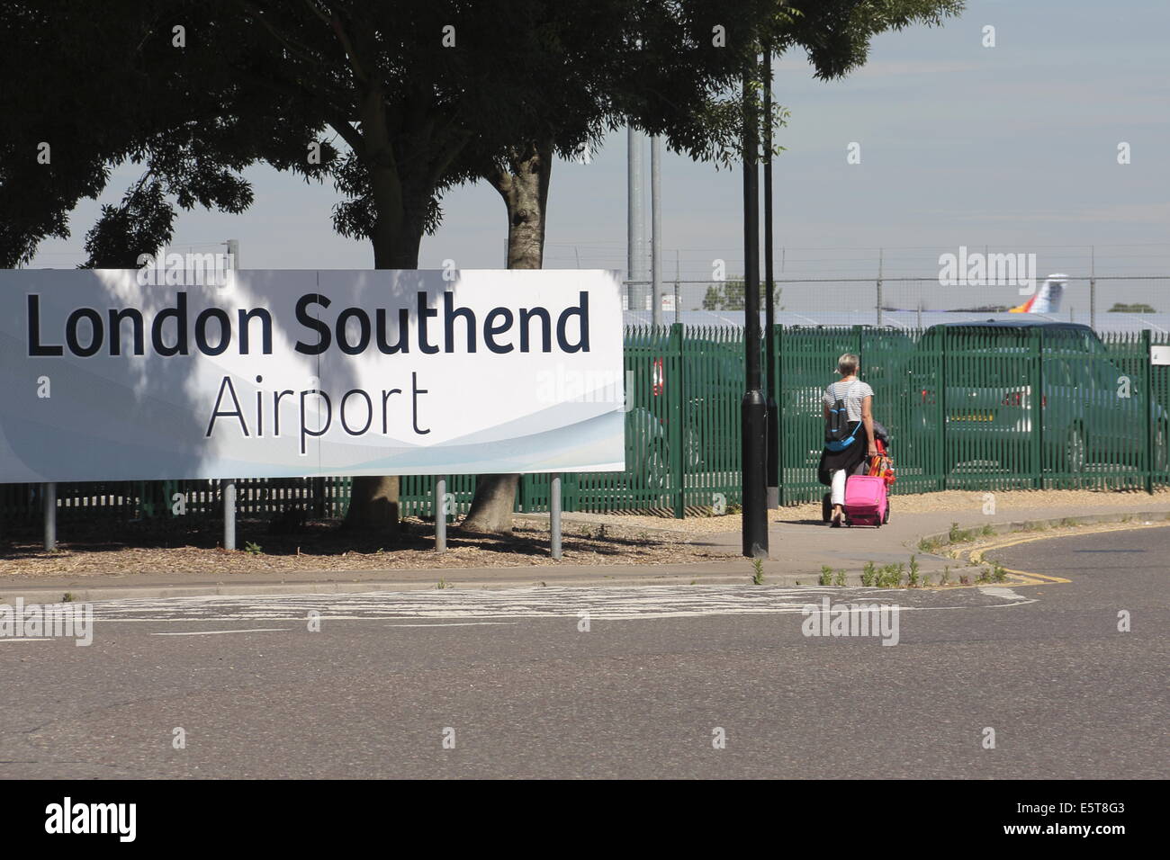 Eine Frau, die Machenschaften eines Koffers, in London Southend Airport. Stockfoto