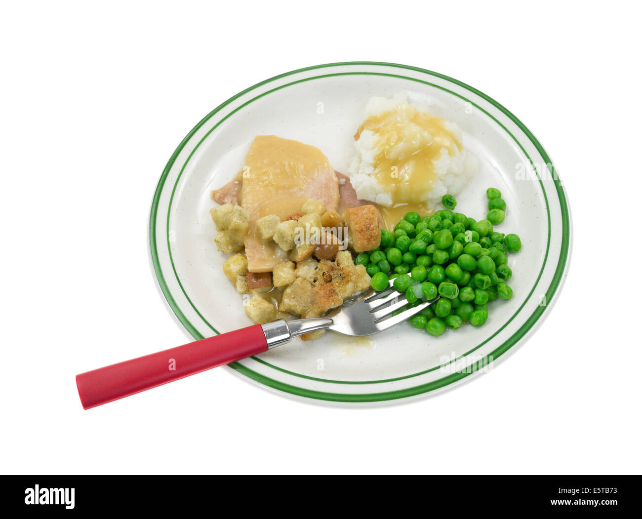 Gekocht in Scheiben geschnitten Türkei in Soße mit Croûtons, Kartoffelpüree und Erbsen auf einem Teller mit roten behandelt Gabel. Stockfoto